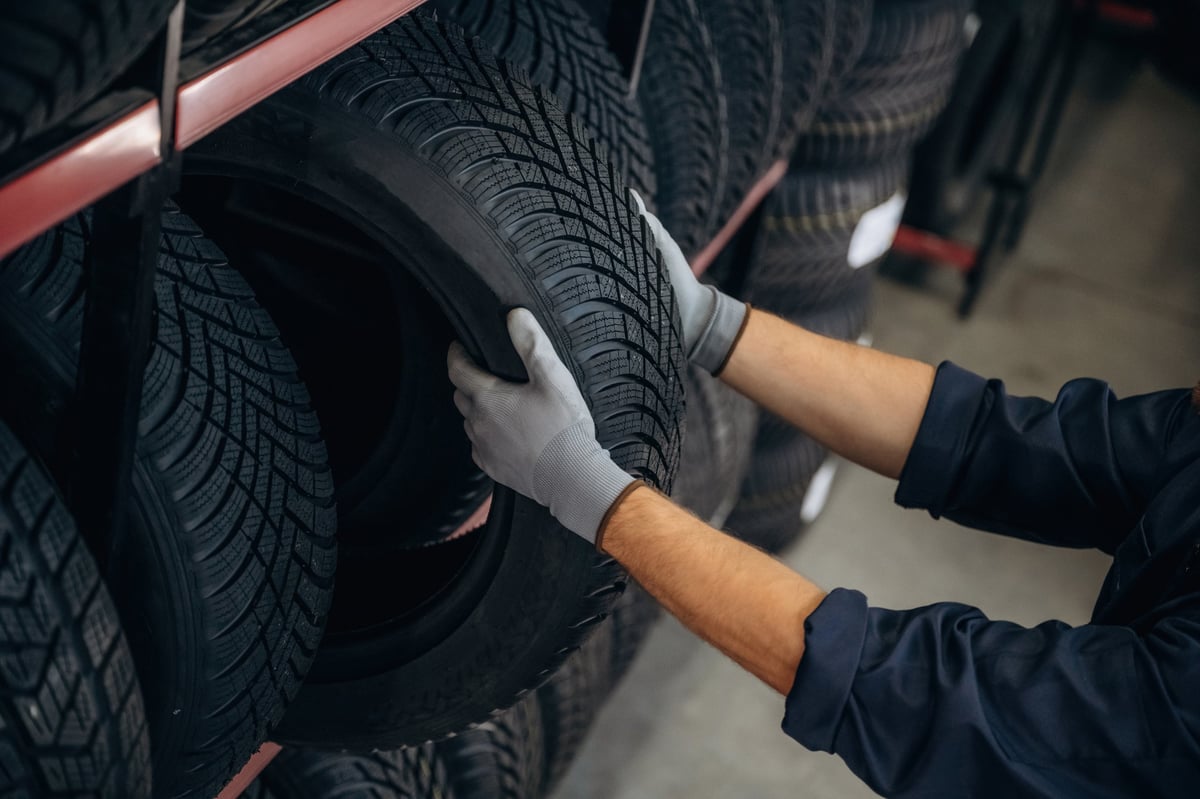 Close up view, taking the tire. Man worker is maintenance station with wheels.
