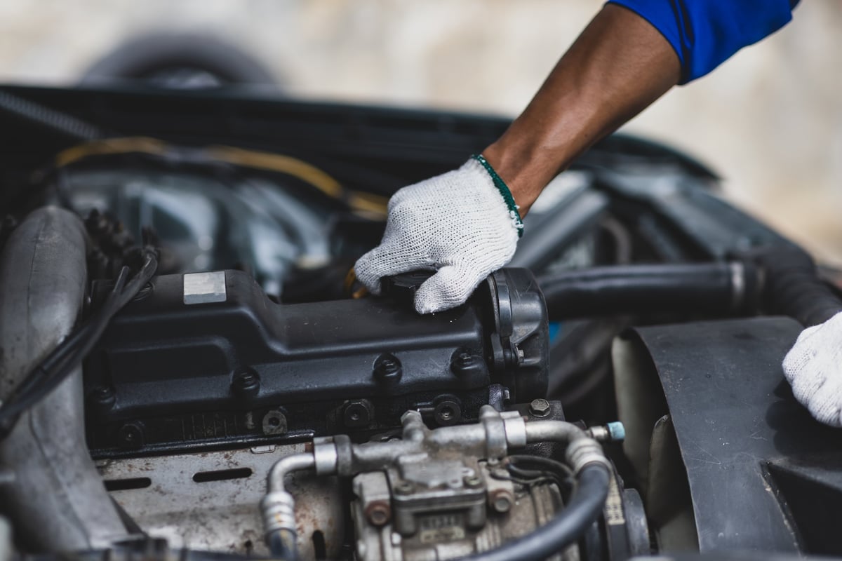 Auto mechanic checking engine and engine oil.