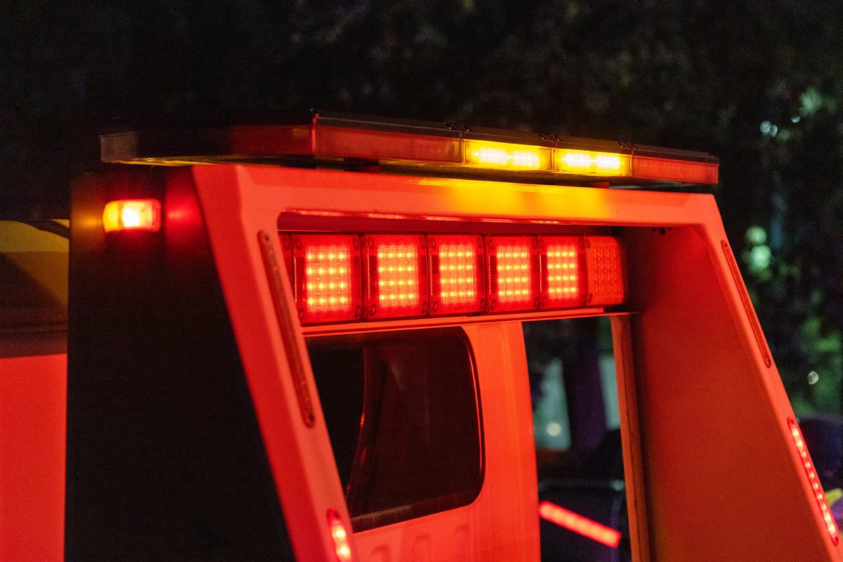 Emergency lights flashing on the roof of a tow truck in attendance at a motor vehicle accident at night