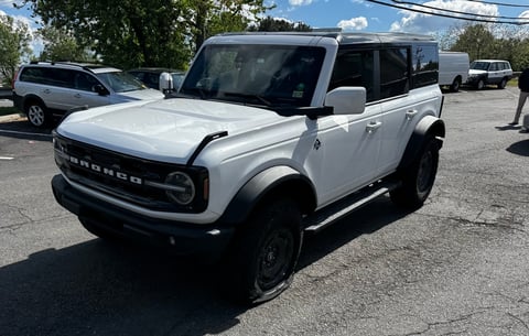 White Ford Bronco SUV parked in a lot with other vehicles visible in the background