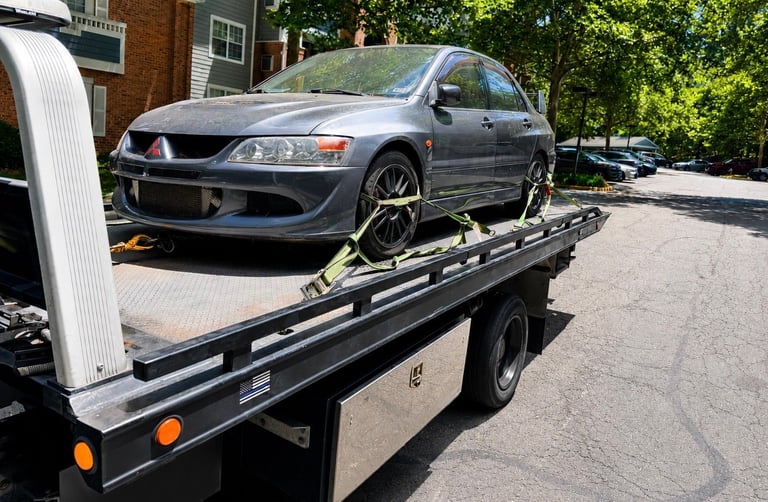 Silver Mitsubishi Lancer Evolution secured on a flatbed tow truck in a residential driveway