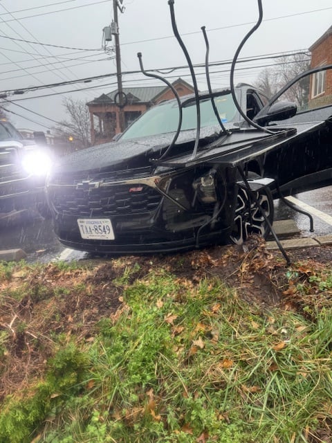Damaged black car crushed by tangled power lines on a residential street