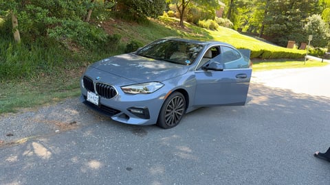 Light blue BMW sedan parked on a tree-lined driveway