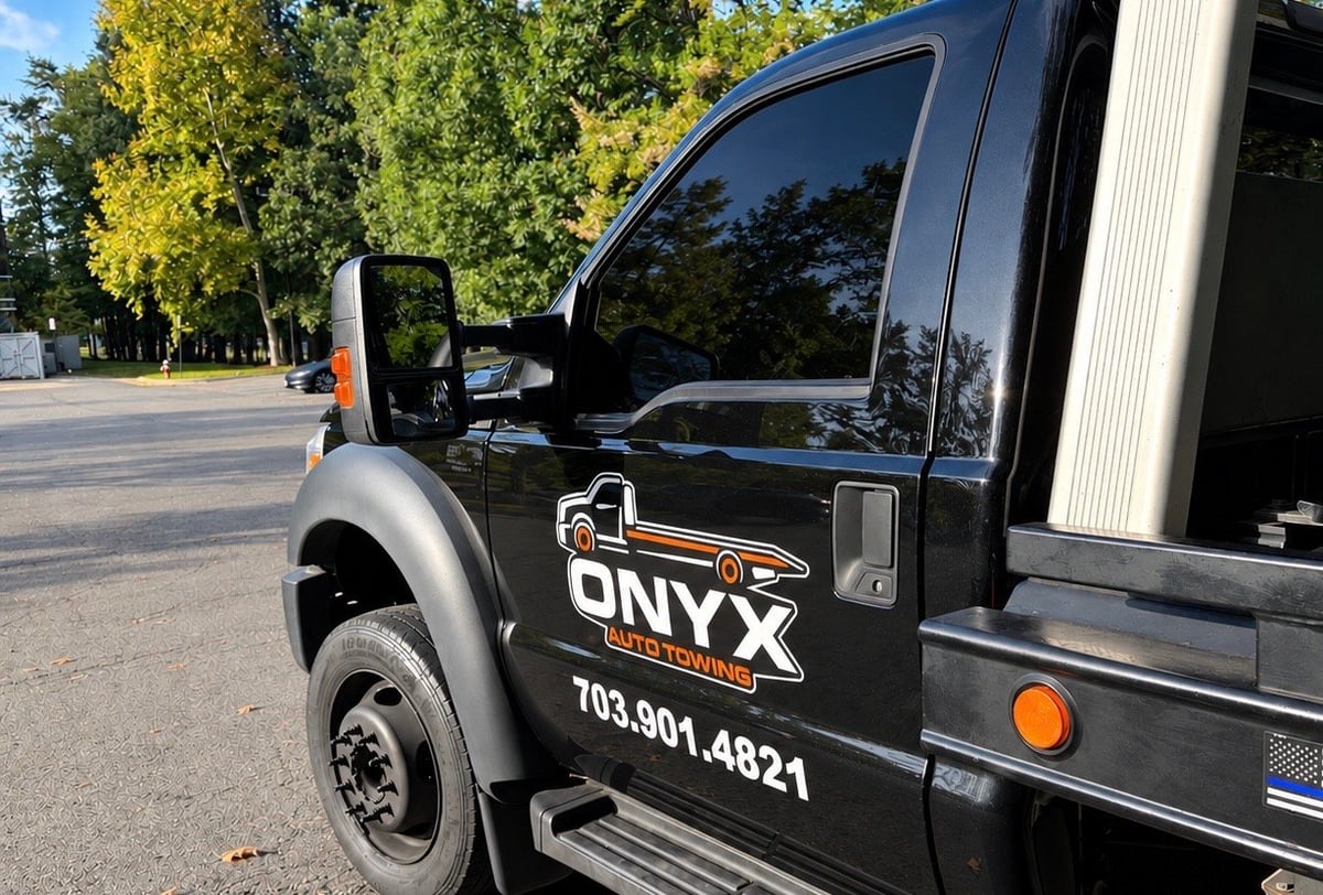 Black Onyx tow truck parked on a tree-lined street with phone number 703.901.4821 displayed on the side